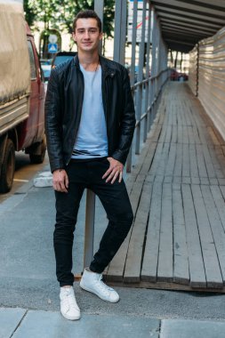 Çekici ve yakışıklı adam girişte duruyor ve beyaz tişört ve siyah deri ceketlerle gülüyor. iletişim.