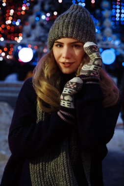 Kış şapkalı güzel bir kız Noel ağacının yanında, kış tatilleri, tatiller ve bir film fotoğrafının altında buğdayla yürüyor.