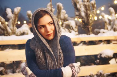 Kış şapkalı güzel bir kız Noel ağacının yanında, kış tatilleri, tatiller ve bir film fotoğrafının altında buğdayla yürüyor.