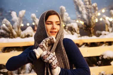Kış şapkalı güzel bir kız Noel ağacının yanında, kış tatilleri, tatiller ve bir film fotoğrafının altında buğdayla yürüyor.
