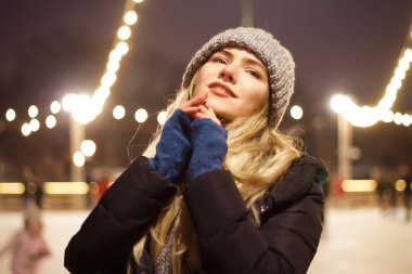 Kış şapkalı güzel bir kız Noel ağacının yanında, kış tatilleri, tatiller ve bir film fotoğrafının altında buğdayla yürüyor.