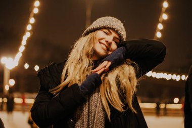 Kış şapkalı güzel bir kız Noel ağacının yanında, kış tatilleri, tatiller ve bir film fotoğrafının altında buğdayla yürüyor.