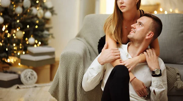 Casal no amor beijos e abraços no sofá perto das luzes da árvore de Natal. Noite de Ano Novo. Natal. . — Fotografia de Stock