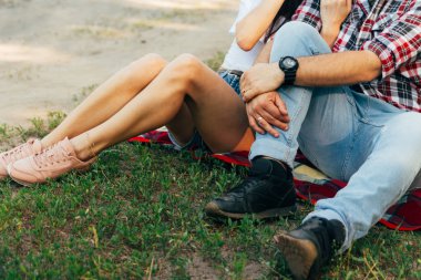 Sevgi dolu çift ormanda kırmızı bir ekose üzerinde oturuyor. Çift öpüşüyor.