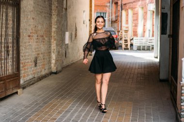 Kız gülümsüyor. Moda 'nın güzel genç bir bayanın duygusal portresi. Şehir portresi. Siyah elbiseli esmer. Beklenti. hayaller