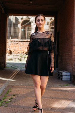 Kız gülümsüyor. Moda 'nın güzel genç bir bayanın duygusal portresi. Şehir portresi. Siyah elbiseli esmer. Beklenti. hayaller