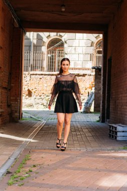 Kız gülümsüyor. Moda 'nın güzel genç bir bayanın duygusal portresi. Şehir portresi. Siyah elbiseli esmer. Beklenti. hayaller