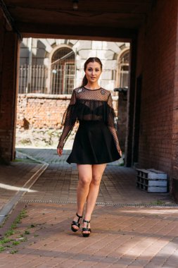 Kız gülümsüyor. Moda 'nın güzel genç bir bayanın duygusal portresi. Şehir portresi. Siyah elbiseli esmer. Beklenti. hayaller