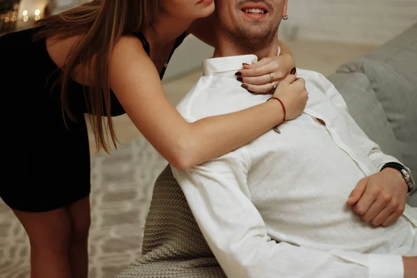 A girl in a black dress hugs the guy from behind, behind the neck and shoulders, care and love. date, valentines day — Stock Photo, Image