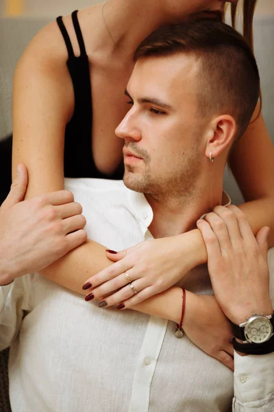 Ein Mädchen in einem schwarzen Kleid umarmt den Typen von hinten, hinter dem Hals und den Schultern, mit Fürsorge und Liebe. Datum, Valentinstag — Stockfoto