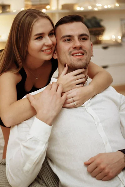 A girl in a black dress hugs the guy from behind, behind the neck and shoulders, care and love. date, valentines day — Stock Photo, Image