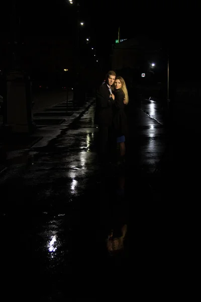 couple in love embracing against a dark background, night, rain, buildings in the city, a park, smiling, attraction. the guy hug the girl. Valentine\'s Day