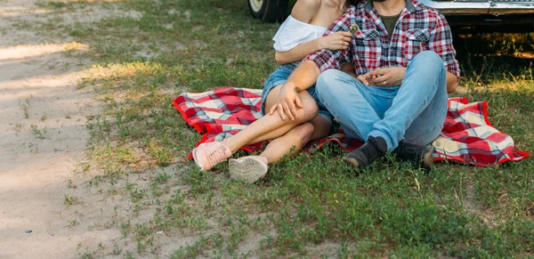 Couple amoureux assis sur un plaid rouge dans les bois et embrace.the couple embrasse — Photo