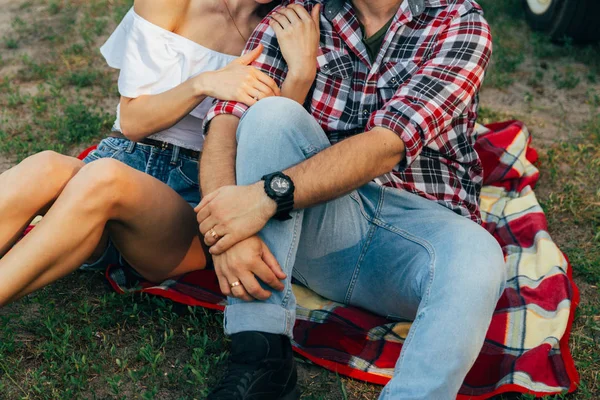 Kärleksfullt par sitter på en röd pläd i skogen och omfamnar. — Stockfoto