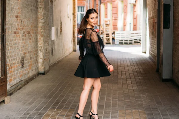 La fille pose des sourires. Portrait émotionnel de la mode portrait élégant de jolie jeune femme. portrait de ville. brunette en robe noire. attente. rêves — Photo