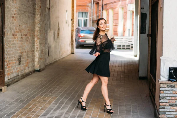 The girl is posing smiles. Emotional portrait of Fashion stylish portrait of pretty young woman. city portrait. brunette in a black dress. expectation. dreams — 스톡 사진