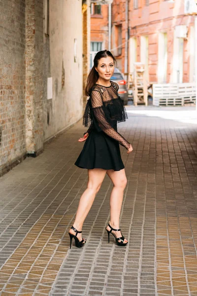The girl is posing smiles. Emotional portrait of Fashion stylish portrait of pretty young woman. city portrait. brunette in a black dress. expectation. dreams — Stock Photo, Image