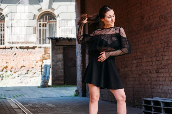 The girl is posing smiles. Emotional portrait of Fashion stylish portrait of pretty young woman. city portrait. brunette in a black dress. expectation. dreams — 스톡 사진