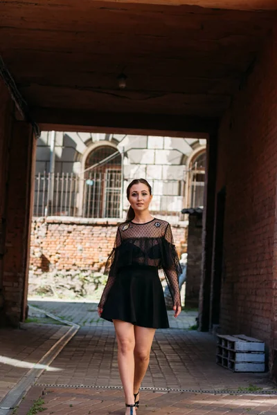 A rapariga está a posar sorrisos. Retrato emocional de moda retrato elegante de mulher muito jovem. retrato da cidade. morena em um vestido preto. Esperança. sonhos — Fotografia de Stock