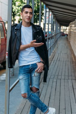 Çekici ve yakışıklı adam girişte duruyor ve beyaz tişört ve siyah deri ceketlerle gülüyor. iletişim.