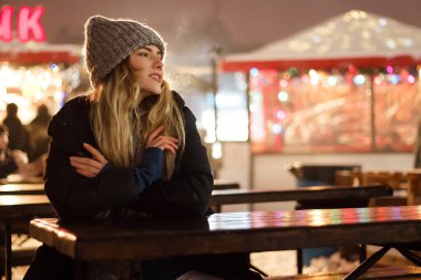 Kış şapkalı güzel bir kız Noel ağacının yanında, kış tatilleri, tatiller ve bir film fotoğrafının altında buğdayla yürüyor.