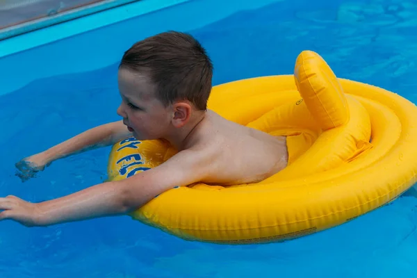 Αγόρι Κολυμπάει Στο Νερό Ένα Φουσκωτό Κίτρινο Κύκλο Στην Πισίνα — Φωτογραφία Αρχείου