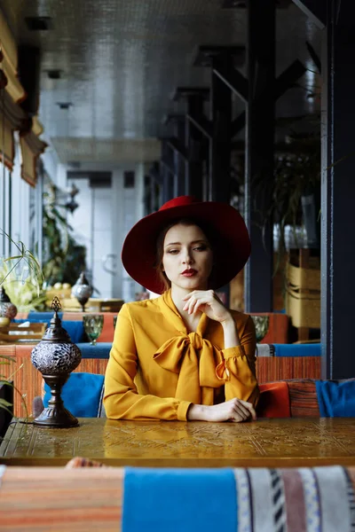 黄色のドレスを着た女の子と帽子はカフェに座ってパンデミックや隔離され. — ストック写真