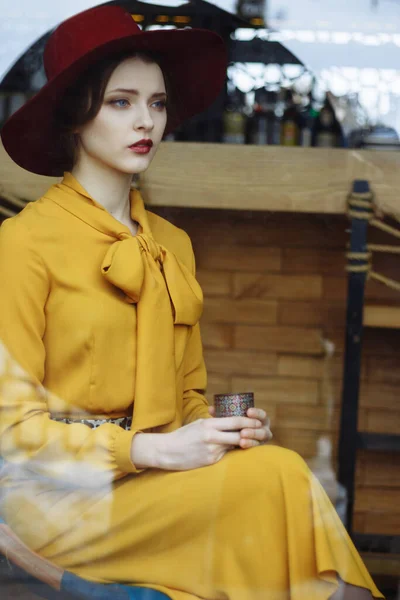 커피 한 잔하고 모자쓴 관능적 인 젊은 여자의 초상이 있는 카페에 있는 여자. 커피를 들고 카페에 있는 아름다운 갈색 머리 여인 — 스톡 사진