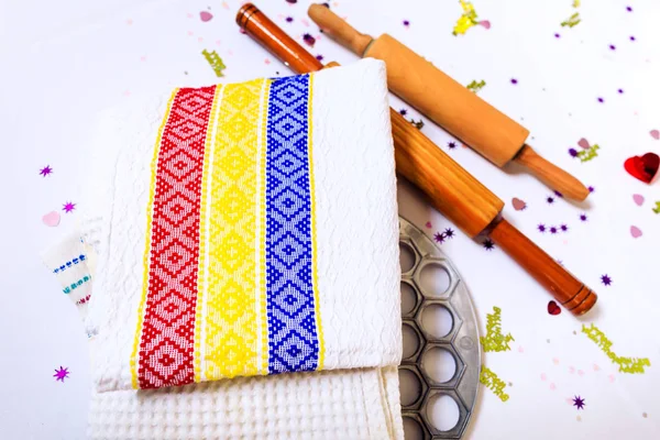 Kitchen towels with Romanian tricolor and a wooden spoon or stick, tools for the dumplings preparation. Shape of dumplings & stick, on background of tricolor dish towels.