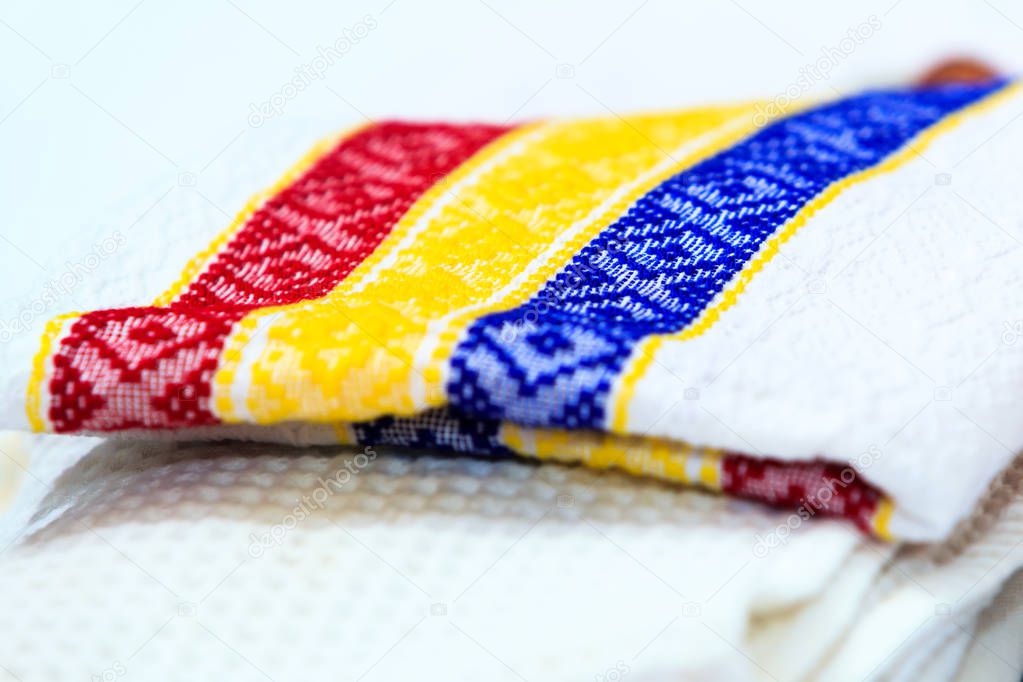Stack of dish towels with Romanian motives of tricolor. Kitchen cloth (napkin). Background for Romanian or Moldovan traditional food. Tricolor checkered dishtowel on white background. 