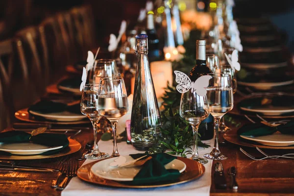 Dinner table setting. Banquet or holiday background in a rustic atmosphere.  Vintage decoration of reception table. Elegant arrangement of the holiday tableware. Wine glasses, plates, forks and green briefcases for event celebration.