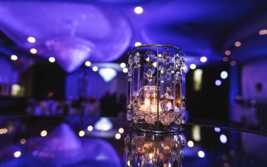 Mor etkinlik odasının arka planında cam mum ışığı. Parti salonunun içinde kristal cam ışıklar. Modern ziyafet restoranında güzel bir menekşe süslemesi. Tatil masası. Olay kutlaması için romantik arkaplan.