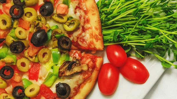 Zeytinli pizza, biberli ve kırmızı domatesli, geleneksel İtalyan yemeği. Restoran masasındaki fırında sebzeli pizzanın en üst görüntüsü. Akdeniz Lezzetli Yemeklerine yakın çekim.  