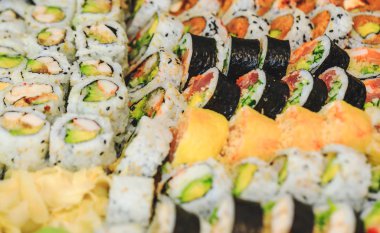 Somon, avokado, ton balığı ve salatalıklı suşi. Pirinçli taze maki ve nori. Suşili lezzetli Japon yemekleri yakın plan çekimde. Sağlıklı lahana ve suşi. Asya lokantası masasında tatil yemeği.. 