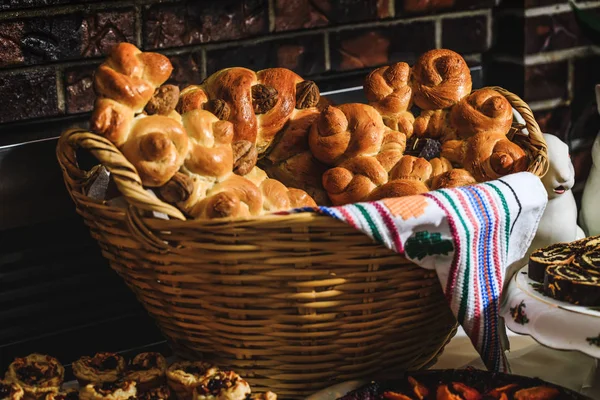 Panini al forno, colaci o torte in cestini di paglia e asciugamano con motivi rustici. Tavolo pasquale con pane tradizionale e autentico cibo rumeno. Pane sotto forma di lumache o piccioni nell'asciugamano colorato con elementi della cultura europea . — Foto Stock