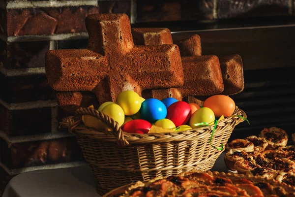 イースターの多色の卵と伝統的な休日の食べ物として焼きたてのクロスパン。イースターケーキやクロスパンや卵を閉じ画像で。自家製ホットクロスパンと素朴なバスケットはイースターの時間の準備ができて. ストックフォト