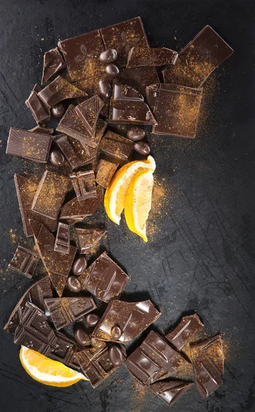 Cracked chocolate with lemon slices on black background