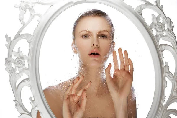 Woman looking through wet glass in frame