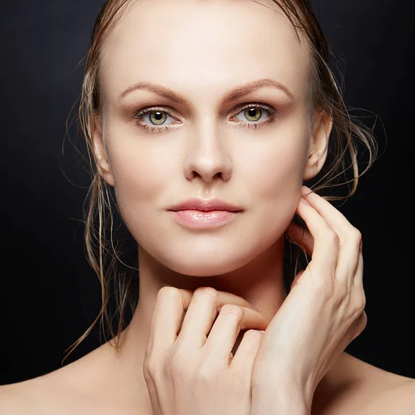 Portrait of young woman with natural makeup and hands near face