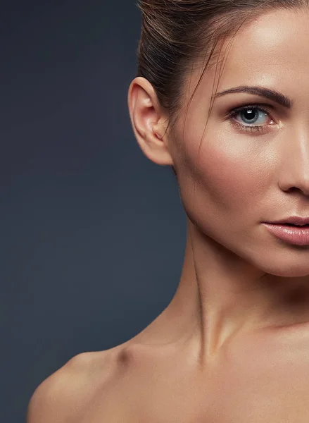 Half face of blond woman with natural makeup on grey background