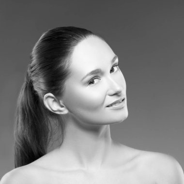 Işık ile genç kadın portresi sırıtıp yüzündeki gri arka plan karşı doğal makyaj ile