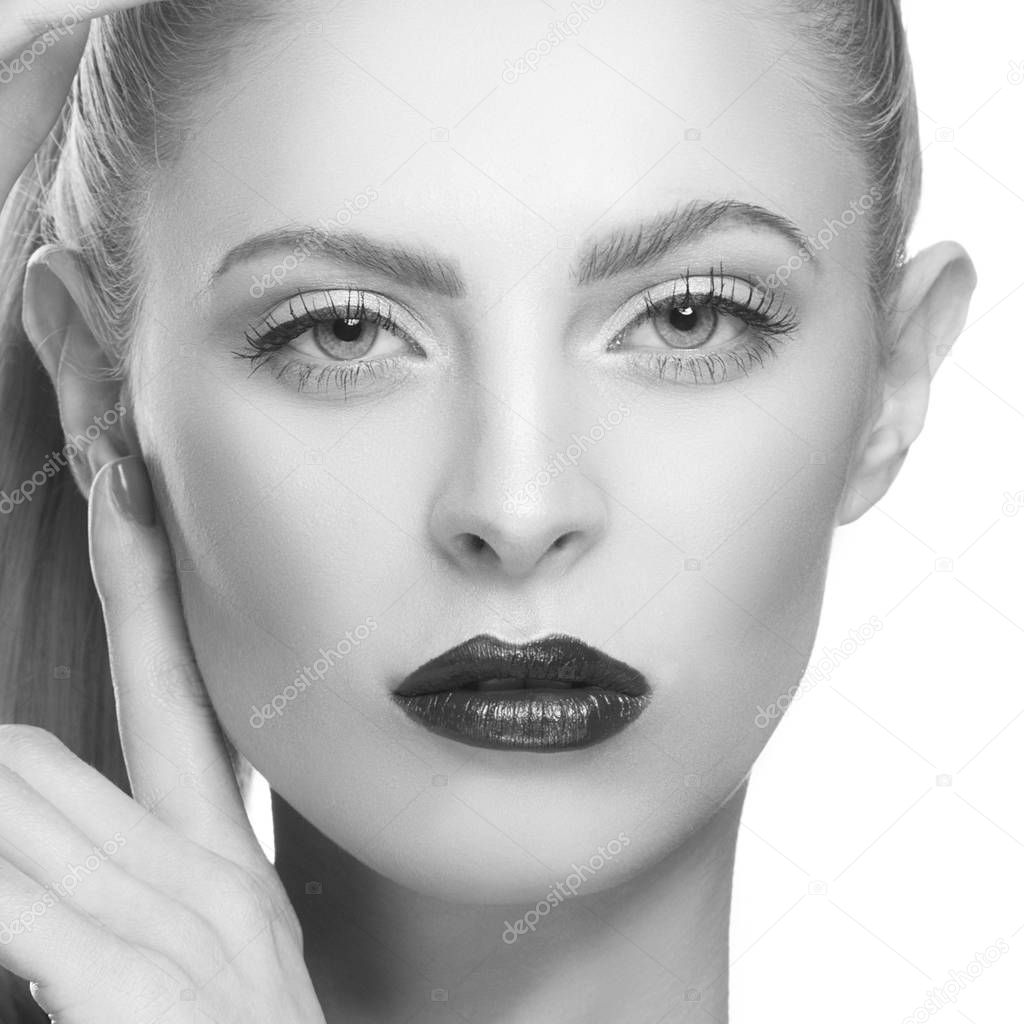Monochrome portrait of young woman with dark lips on white background