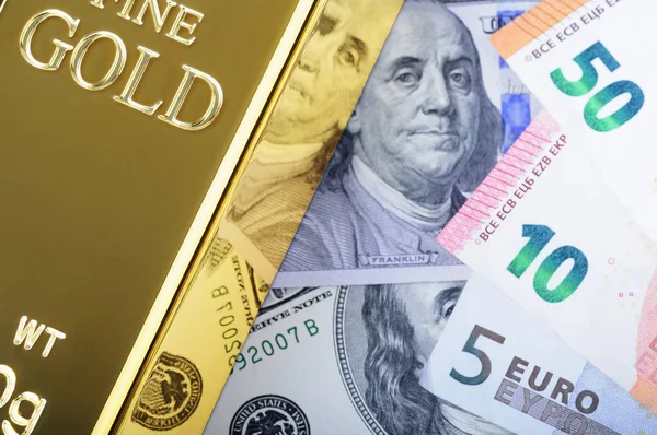 Gold metal ingot bullion on the background of dollar and euro bills