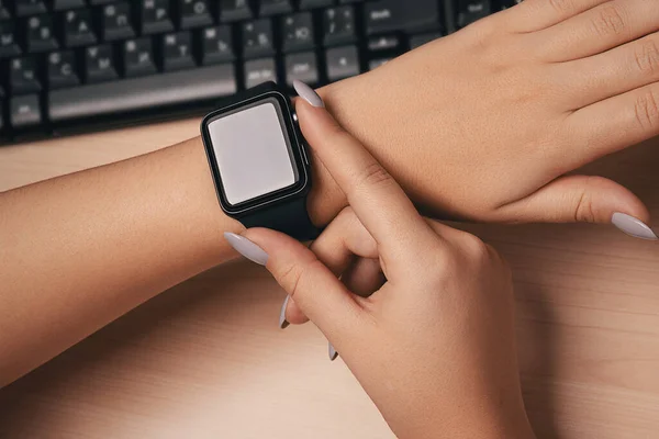 Woman touching smart watch hand on work desk