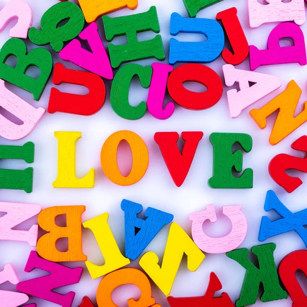 The word love is made up of letters of the alphabet, randomly scattered macro photography isolated on a white background. Close up.