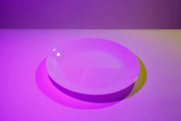 用紫外对比色的两盏灯点燃的简单陶瓷白碟的抽象图片 明亮的粉红色和石灰绿色 — 图库照片