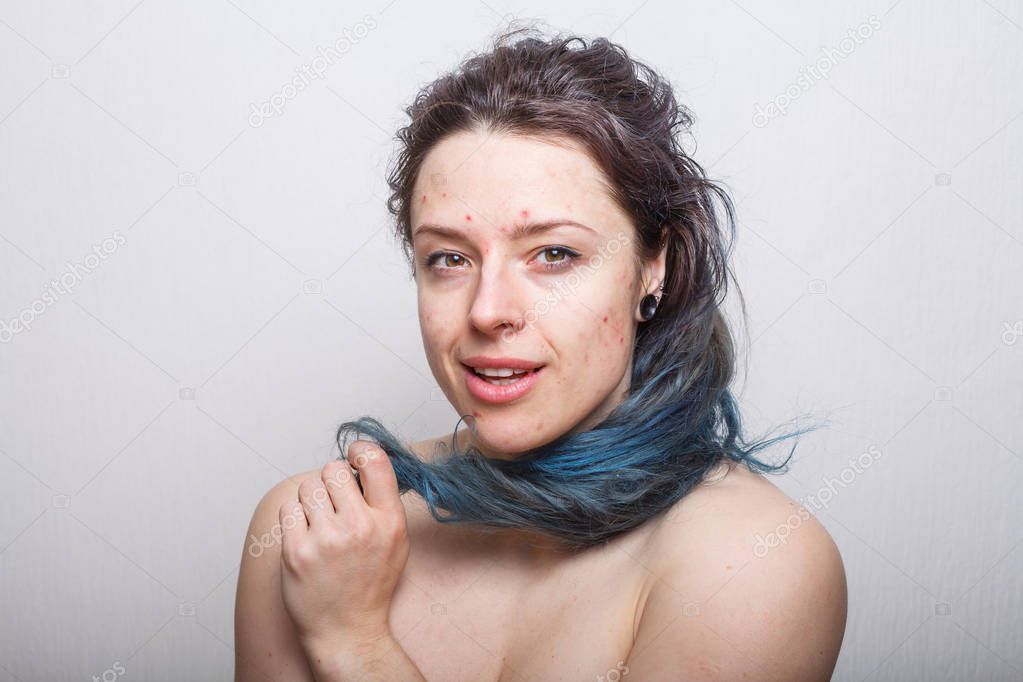 Young woman rolling her colorful but damaged messy hair on her finger. Absolutely no retouching.