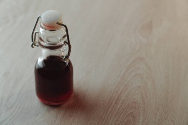 Koyu kırmızı içecekle doldurulmuş küçük, yeniden kullanılabilir cam şişe.