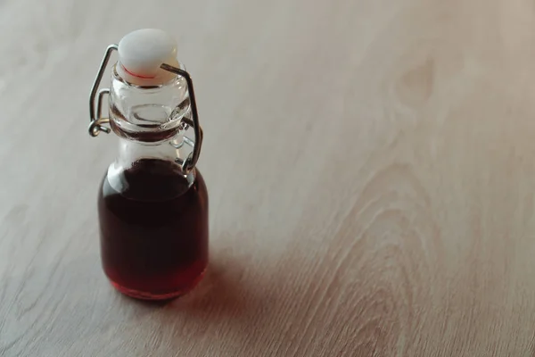 Маленькая стеклянная бутылка многоразового использования с темно-красным напитком — стоковое фото