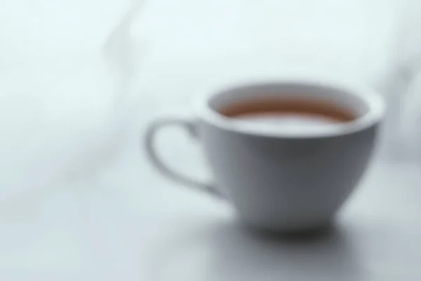 Blurred background image of simple white cup filled with tea